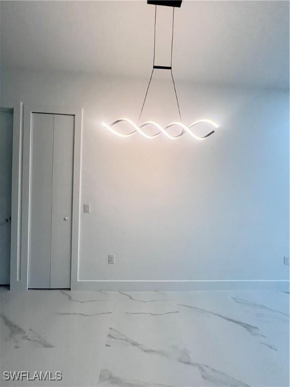 unfurnished dining area featuring baseboards and marble finish floors
