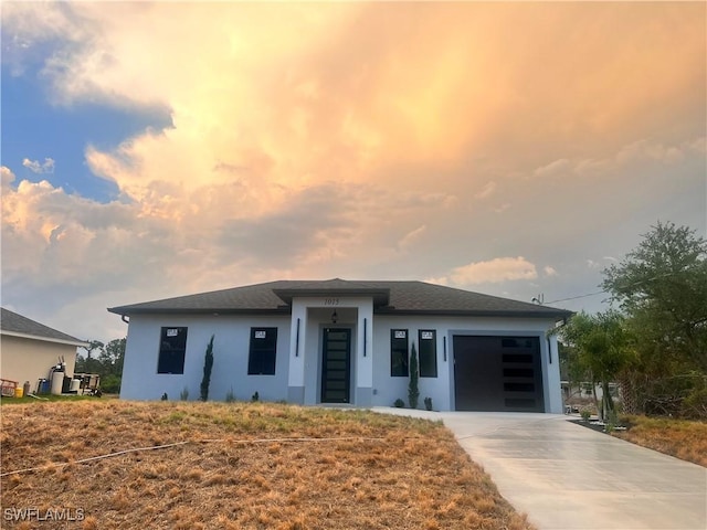 prairie-style home featuring a garage, stucco siding, and concrete driveway