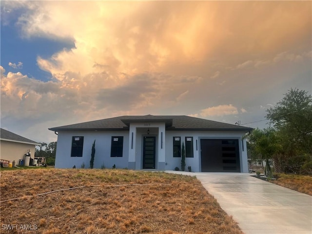 prairie-style home featuring a garage, stucco siding, and concrete driveway