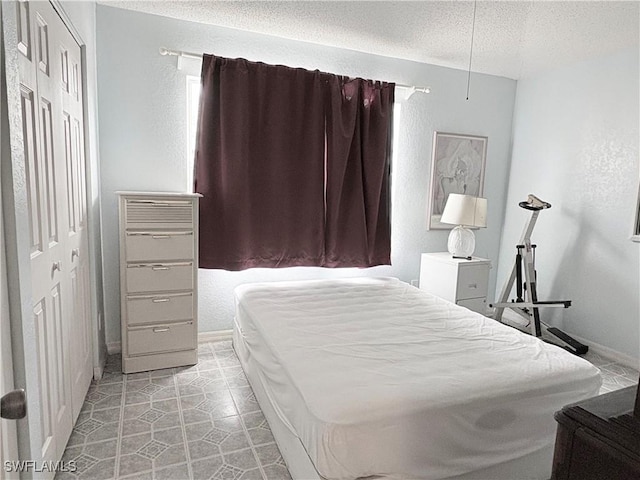 1096 Woodshire Ln Unit C205, Naples, FL 34105 - bedroom featuring a textured ceiling, a closet, baseboards, and light tile patterned flooring