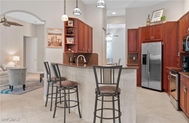 20408 Foxworth Cir, Estero, FL 33928 - kitchen featuring appliances with stainless steel finishes, a ceiling fan, a breakfast bar, tasteful backsplash, and light tile patterned flooring