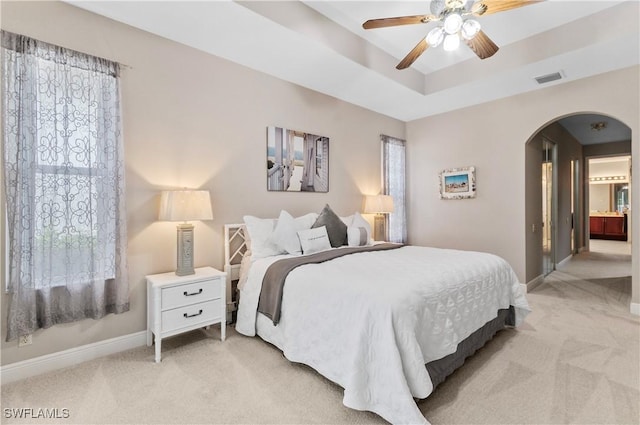 20408 Foxworth Cir, Estero, FL 33928 - bedroom featuring arched walkways, light colored carpet, baseboards, a tray ceiling, and ceiling fan