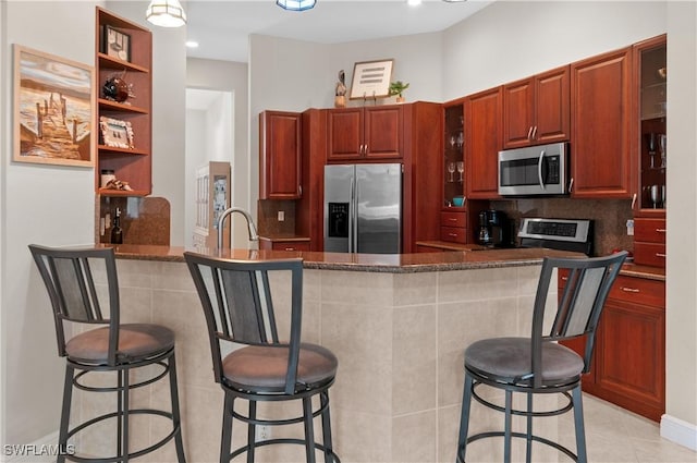 20408 Foxworth Cir, Estero, FL 33928 - kitchen with stainless steel appliances, glass insert cabinets, a kitchen breakfast bar, light tile patterned floors, and open shelves