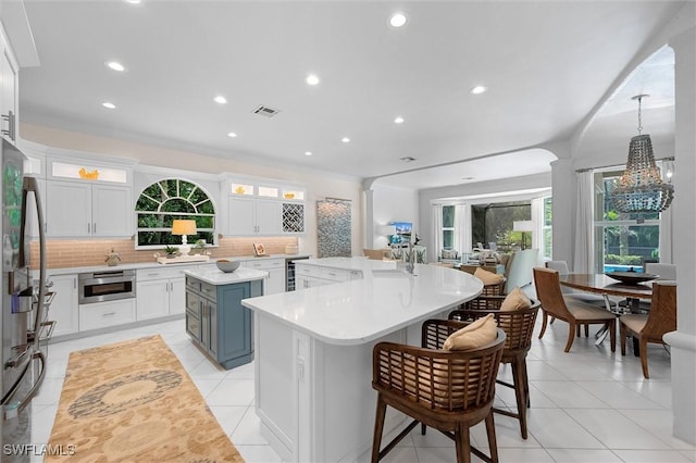 2026 Merlin Ct, Naples, FL 34105 - kitchen with a center island, a chandelier, stainless steel appliances, tasteful backsplash, and white cabinets