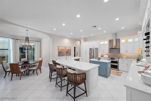 2026 Merlin Ct, Naples, FL 34105 - kitchen with stainless steel appliances, a large island, wall chimney exhaust hood, a chandelier, and a sink