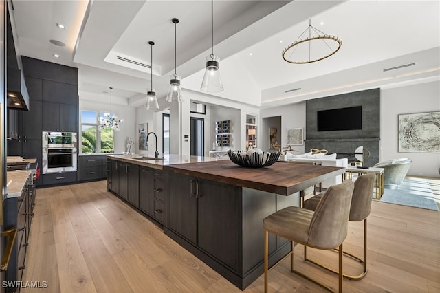 115 E Ave, Naples, FL 34108 - kitchen with a chandelier, a sink, butcher block countertops, a tray ceiling, and a spacious island