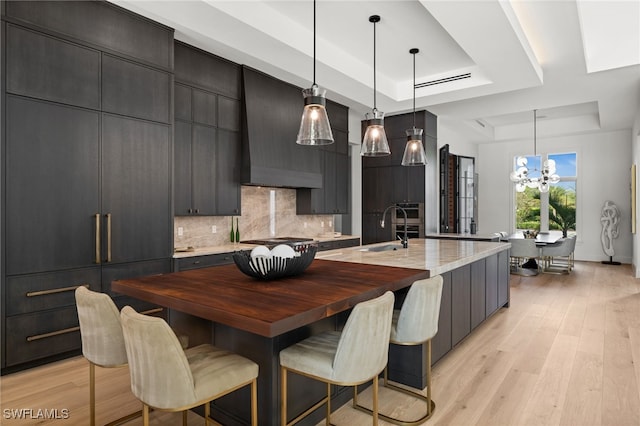 115 E Ave, Naples, FL 34108 - kitchen with a tray ceiling, a sink, a chandelier, backsplash, and stainless steel gas stovetop