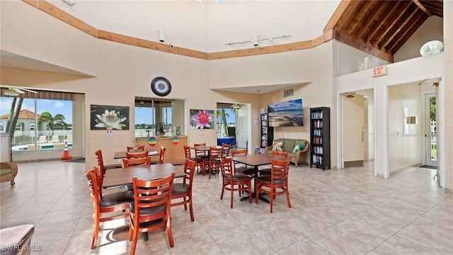 dining area with high vaulted ceiling, healthy amount of natural light, and light tile patterned floors