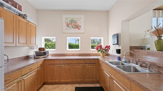 kitchen with a sink, light tile patterned floors, and brown cabinetry
