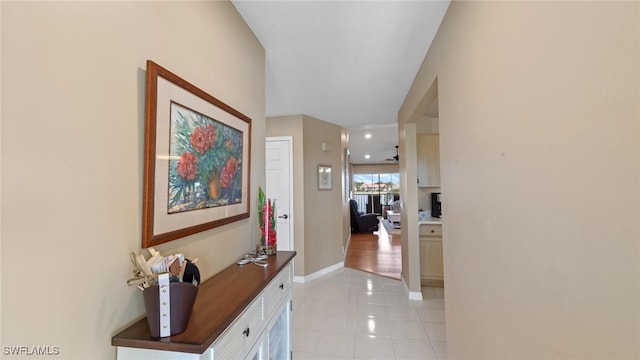 hallway with light tile patterned flooring and baseboards
