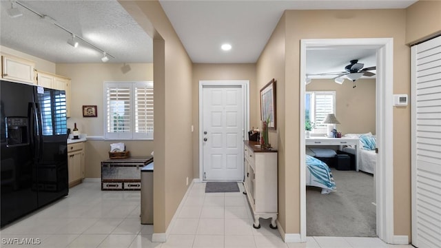 foyer with a ceiling fan, baseboards, a textured ceiling, and light tile patterned floors