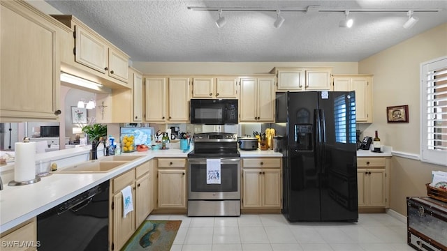 kitchen with black appliances, track lighting, a sink, light countertops, and light brown cabinetry