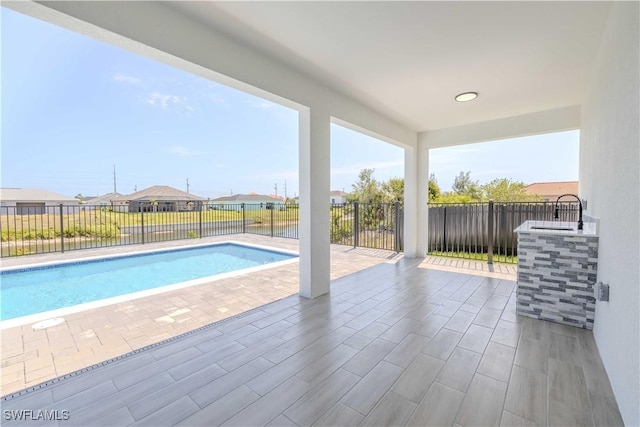 view of swimming pool featuring a patio, a sink, and a fenced backyard