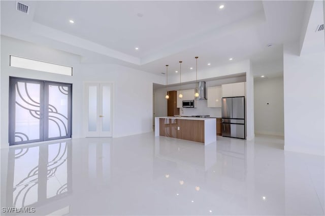 kitchen featuring appliances with stainless steel finishes, modern cabinets, a raised ceiling, wall chimney exhaust hood, and recessed lighting
