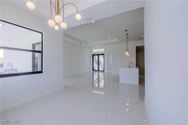 empty room with a sink, recessed lighting, a tray ceiling, and baseboards