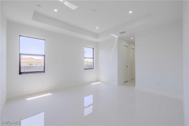 unfurnished room featuring a raised ceiling, recessed lighting, and tile patterned flooring