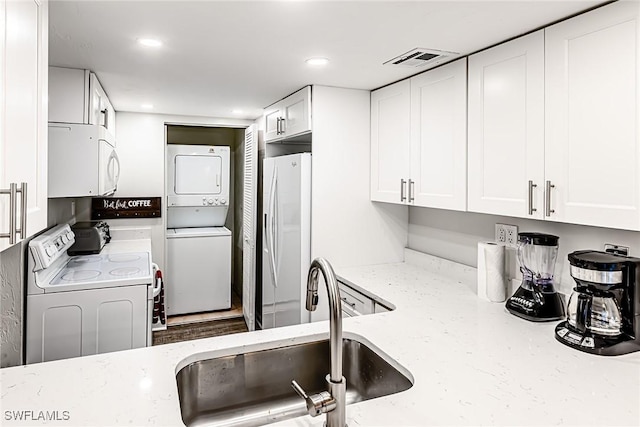 20 Greenbrier St Unit 3-105, Marco Island, FL 34145 - kitchen featuring estacked washer and dryer, white appliances, a sink, white cabinets, and light stone countertops