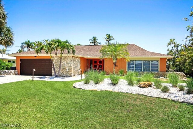 single story home featuring a front yard, an attached garage, and driveway