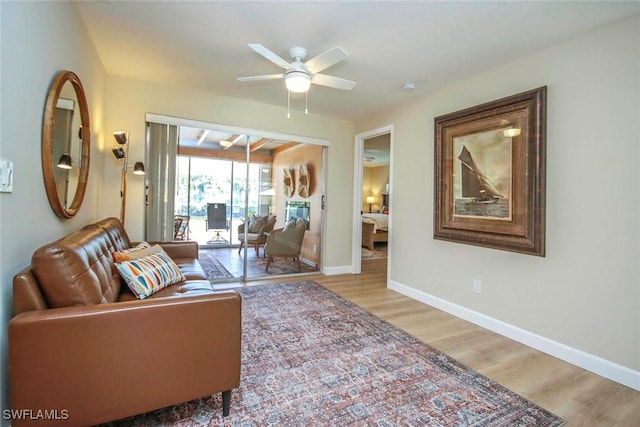 living room with ceiling fan, light wood-type flooring, and baseboards