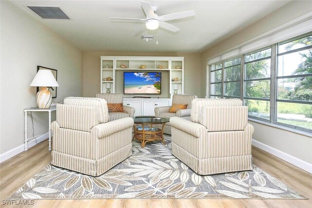 living area featuring baseboards, ceiling fan, and wood finished floors