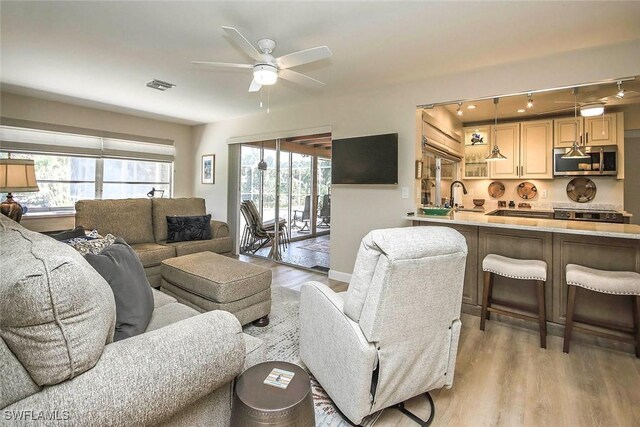 living room featuring light wood finished floors, ceiling fan, and plenty of natural light