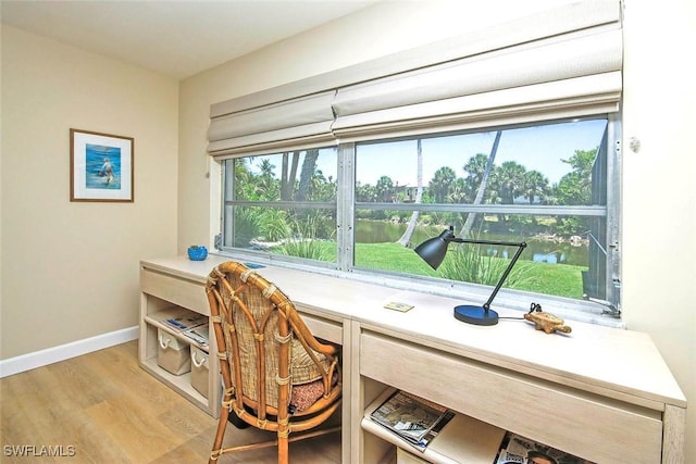 home office featuring baseboards, light wood-style floors, and built in desk