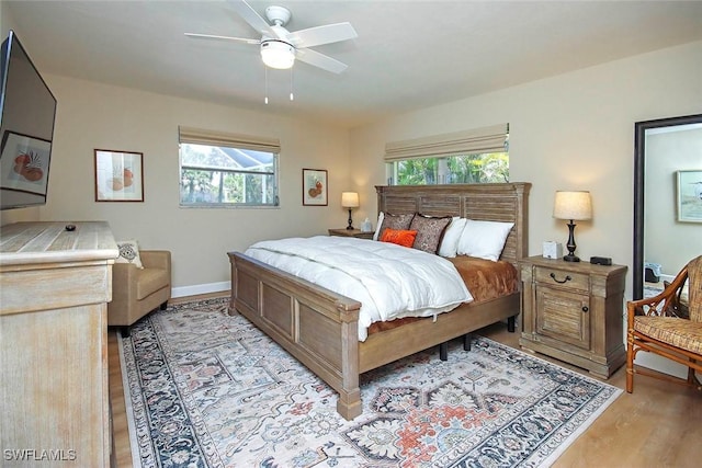 bedroom with light wood-style flooring, multiple windows, ceiling fan, and baseboards