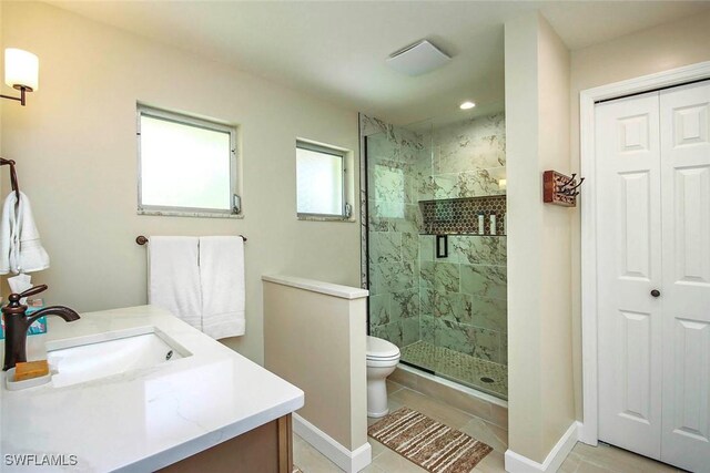 bathroom with a shower stall, toilet, vanity, tile patterned floors, and baseboards