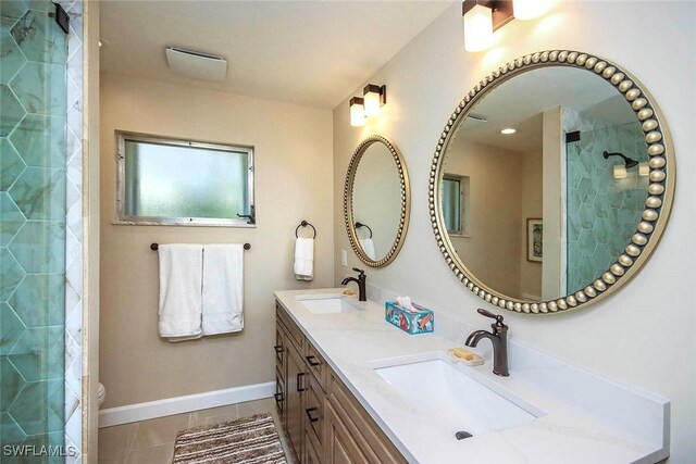 bathroom featuring tile patterned floors, baseboards, tiled shower, and double vanity