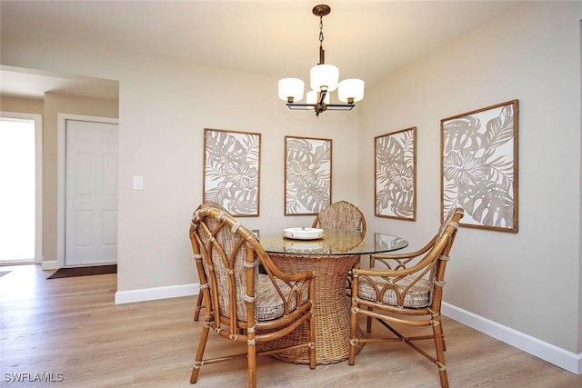 dining room with a chandelier, light wood finished floors, and baseboards