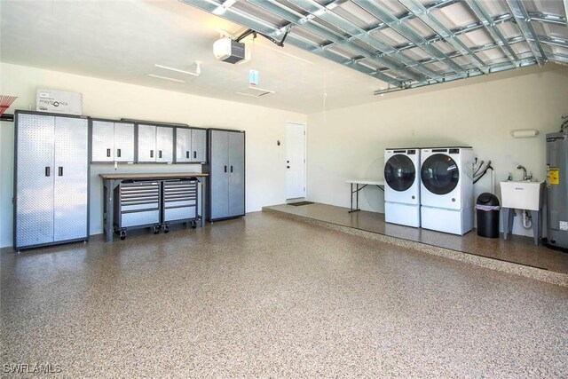 garage with washing machine and clothes dryer, a garage door opener, a sink, and water heater