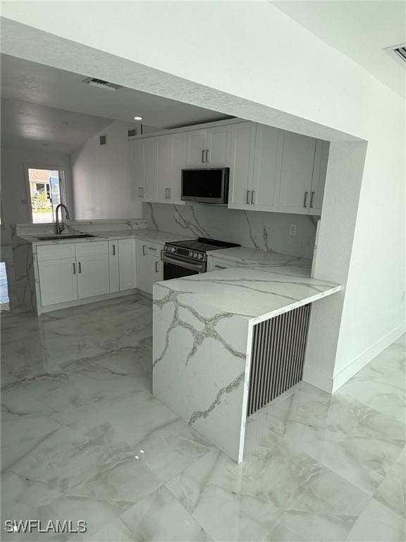 2823 Janet St, Matlacha, FL 33993 - kitchen featuring stainless steel appliances, a peninsula, light stone countertops, and light marble finish floors