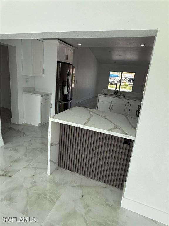 2823 Janet St, Matlacha, FL 33993 - kitchen featuring refrigerator with ice dispenser, light marble finish flooring, light stone counters, white cabinetry, and a peninsula