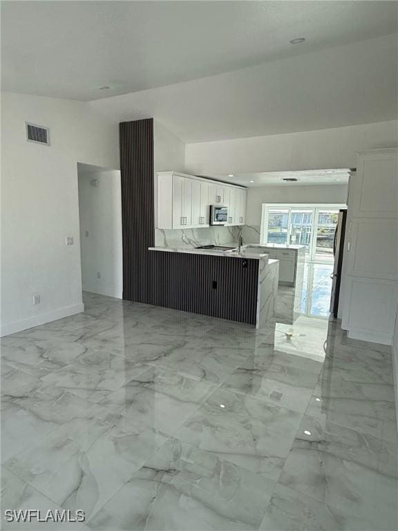 2823 Janet St, Matlacha, FL 33993 - unfurnished living room featuring baseboards, light marble finish flooring, and lofted ceiling
