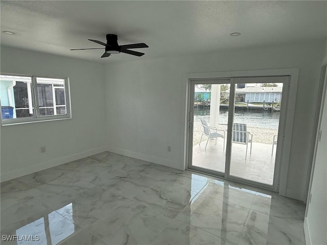2823 Janet St, Matlacha, FL 33993 - empty room featuring baseboards, a ceiling fan, marble look tile flooring, a water view, and a textured ceiling