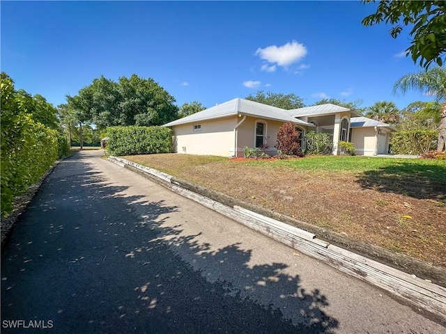 3790 35th Ave NE, Naples, FL 34120 - view of side of home featuring stucco siding, a metal roof, and a garage