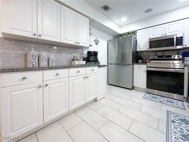 3790 35th Ave NE, Naples, FL 34120 - kitchen with stainless steel appliances, white cabinetry, backsplash, dark stone countertops, and light tile patterned flooring