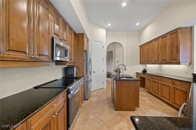 5687 Whispering Willow Way, Fort Myers, FL 33908 - kitchen with appliances with stainless steel finishes, a sink, an island with sink, dark stone countertops, and brown cabinetry
