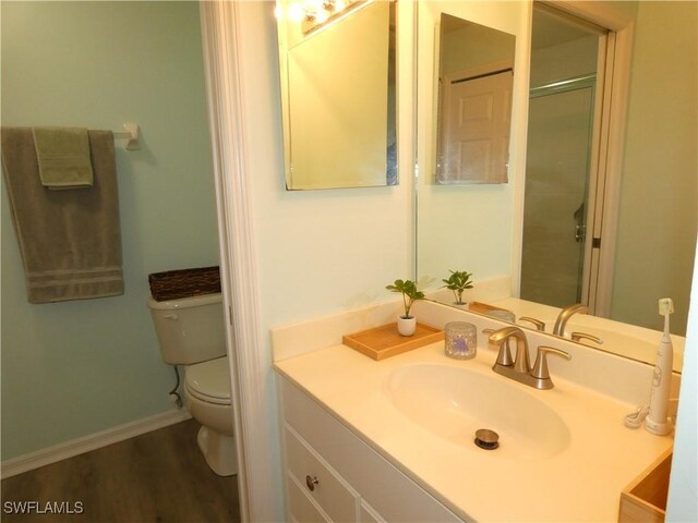 bathroom with toilet, vanity, and wood finished floors