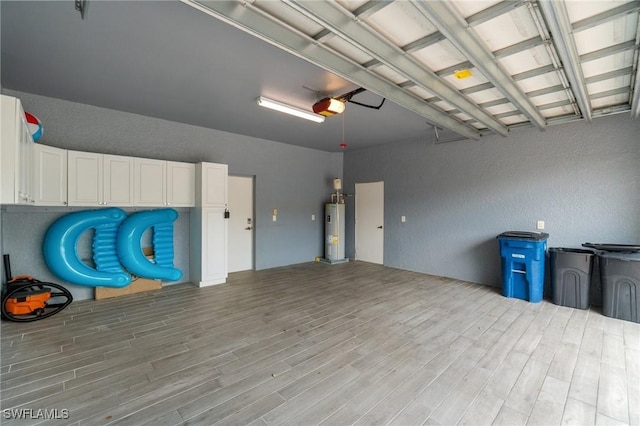garage featuring a garage door opener, water heater, and a textured wall