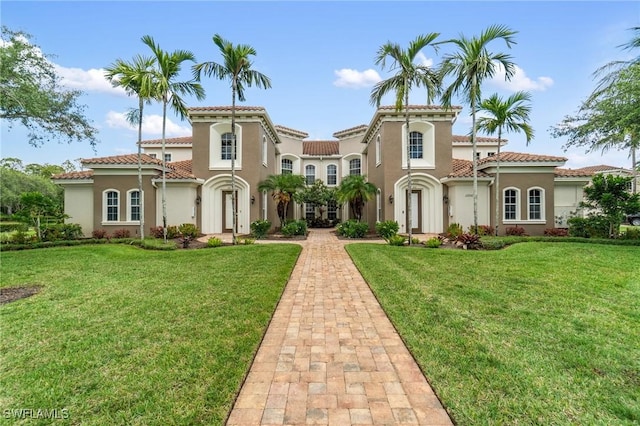 mediterranean / spanish house with stucco siding, a front lawn, and a tiled roof