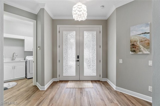 foyer entrance featuring french doors, washer / dryer, crown molding, light wood-type flooring, and baseboards
