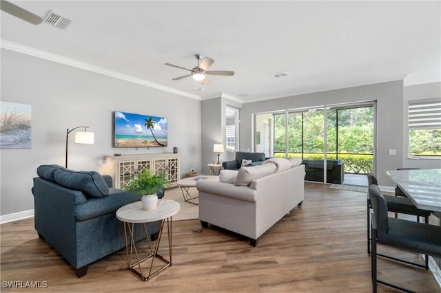 living area featuring baseboards, ornamental molding, wood finished floors, and a ceiling fan