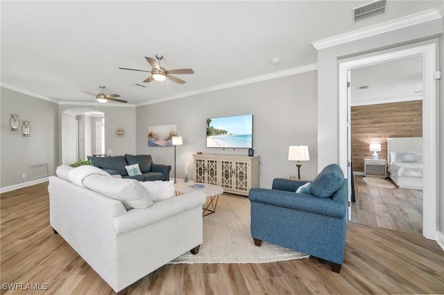 living room with arched walkways, wood finished floors, ceiling fan, crown molding, and baseboards