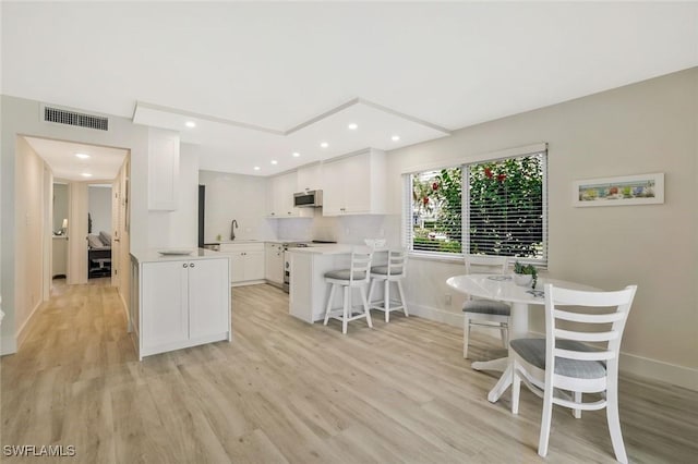 354 Harbour Dr Unit 354, Naples, FL 34103 - kitchen with stainless steel microwave, light wood-style floors, white cabinetry, a peninsula, and recessed lighting
