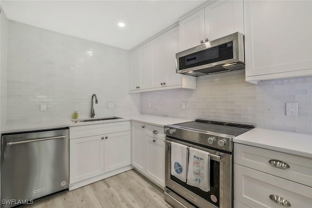 354 Harbour Dr Unit 354, Naples, FL 34103 - kitchen with appliances with stainless steel finishes, a sink, decorative backsplash, light countertops, and white cabinetry