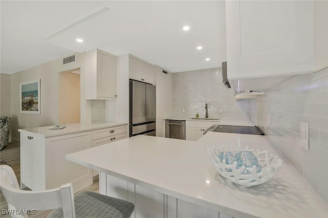354 Harbour Dr Unit 354, Naples, FL 34103 - kitchen featuring appliances with stainless steel finishes, a peninsula, a sink, tasteful backsplash, and light countertops
