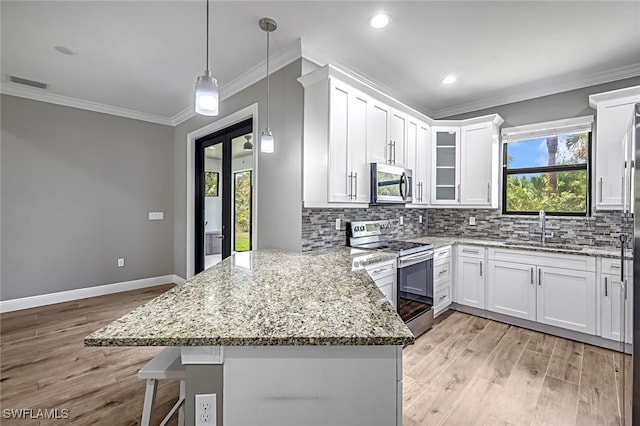 79 41st Ave NE, Naples, FL 34120 - kitchen featuring stainless steel appliances, a peninsula, a sink, white cabinets, and ornamental molding