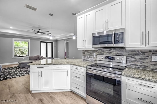 79 41st Ave NE, Naples, FL 34120 - kitchen with stainless steel appliances, a peninsula, open floor plan, white cabinetry, and a ceiling fan