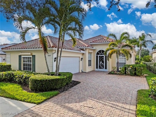 mediterranean / spanish home featuring stucco siding, an attached garage, driveway, and a tiled roof